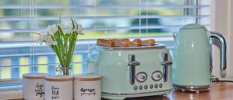 A kitchen counter with a vintage-style toaster, a kettle, and three jars with labels.