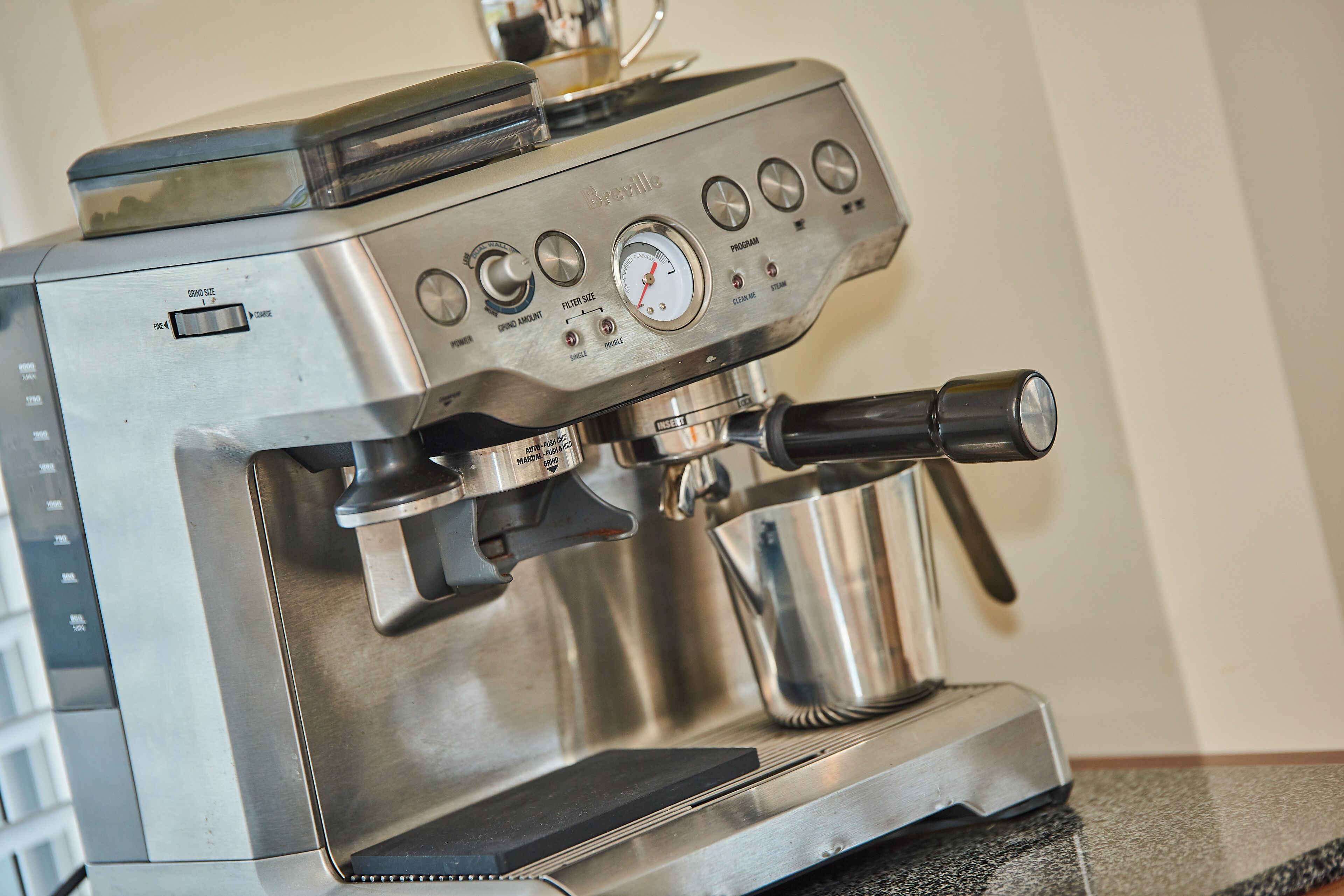 A Breville espresso machine with a digital display, control panel, and steam wand.