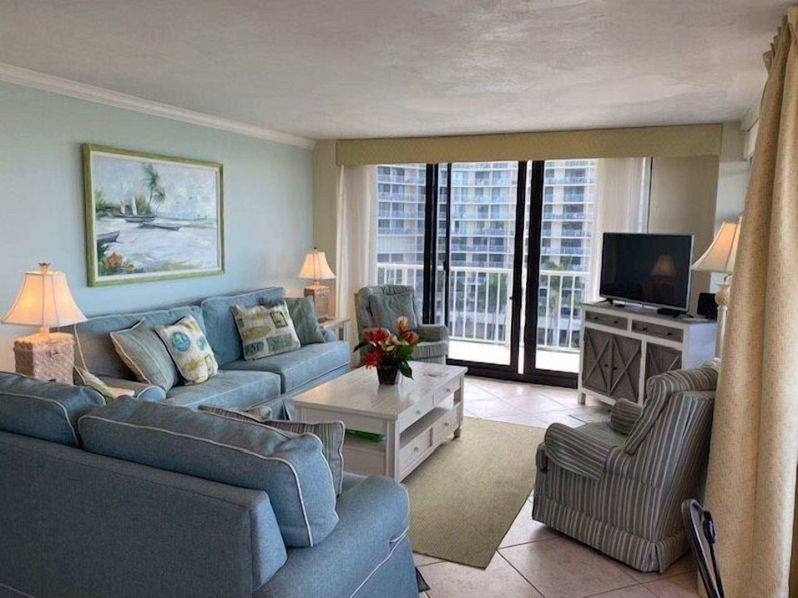 A living room with a sofa, armchairs, a coffee table, and a TV.