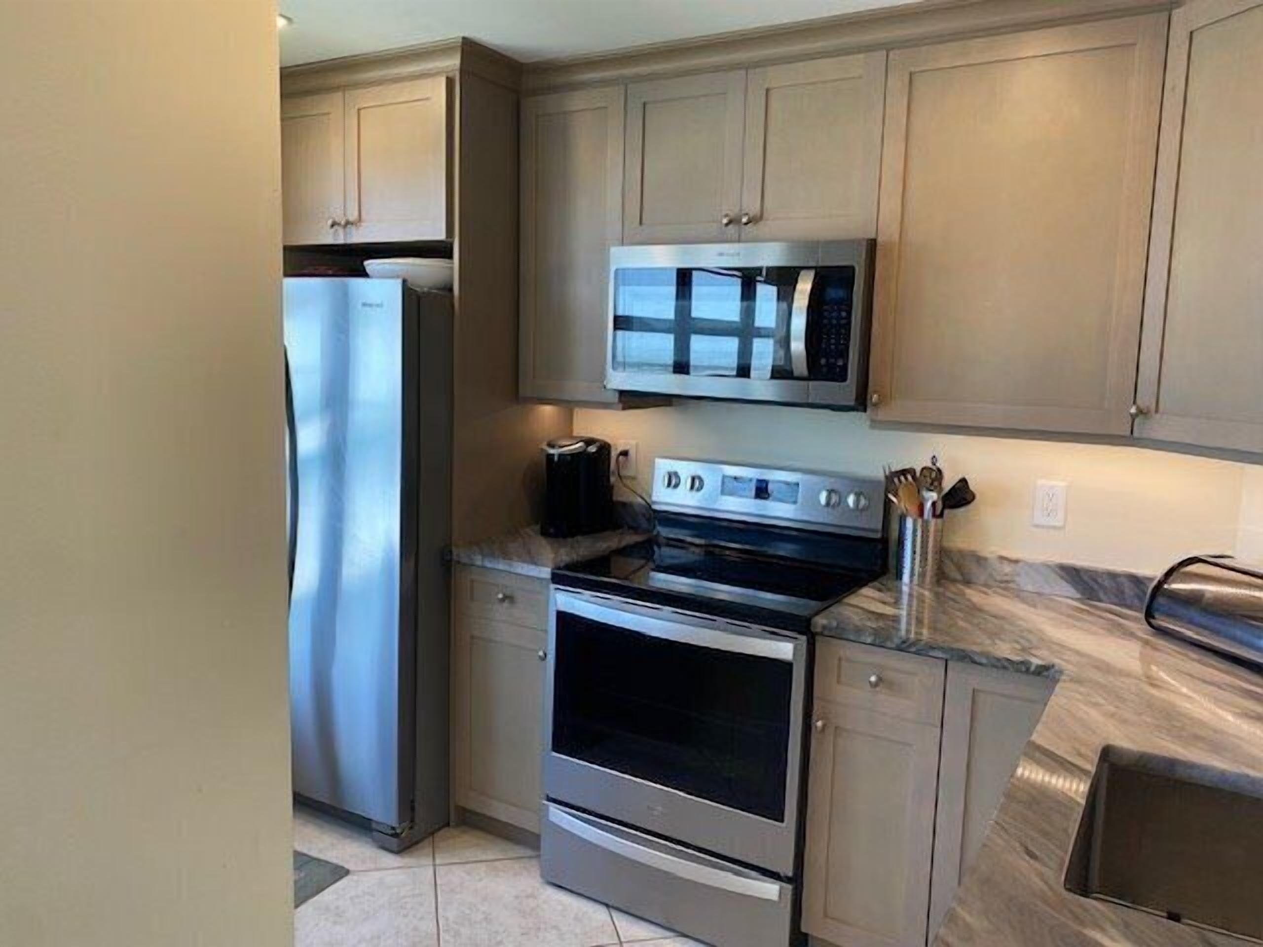 A modern kitchen with stainless steel appliances, including a refrigerator, microwave, and oven.