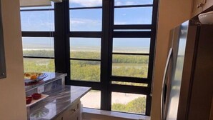 A kitchen with a large window offering a view of a flat landscape. - 2/2 condo, with fantastic views of the beach (Marco Island)