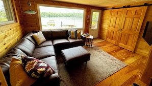 Un interior de cabaña acogedor con un sofá de cuero modular, una mesita y una puerta grande de madera.