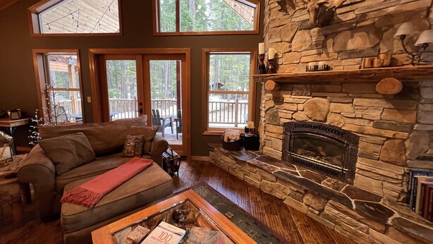 A cozy living room with a stone fireplace, large windows, and a wooden ceiling. - Beautiful 5 Star Guest Cabin in the Mountains, steps from Lake Cle Elum (Ronald)