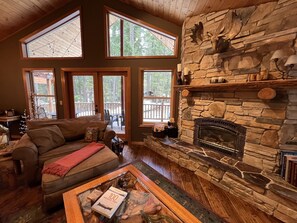 A cozy living room with a stone fireplace, large windows, and a wooden ceiling. - Beautiful 5 Star Guest Cabin in the Mountains, steps from Lake Cle Elum (Ronald)