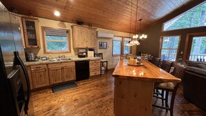 A spacious kitchen with wooden cabinets, a central island, and large windows offering views of the outdoors. - Beautiful 5 Star Guest Cabin in the Mountains, steps from Lake Cle Elum (Ronald)
