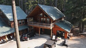 A two-story log cabin with a balcony, a carport, and a gravel driveway. - Beautiful 5 Star Guest Cabin in the Mountains, steps from Lake Cle Elum (Ronald)