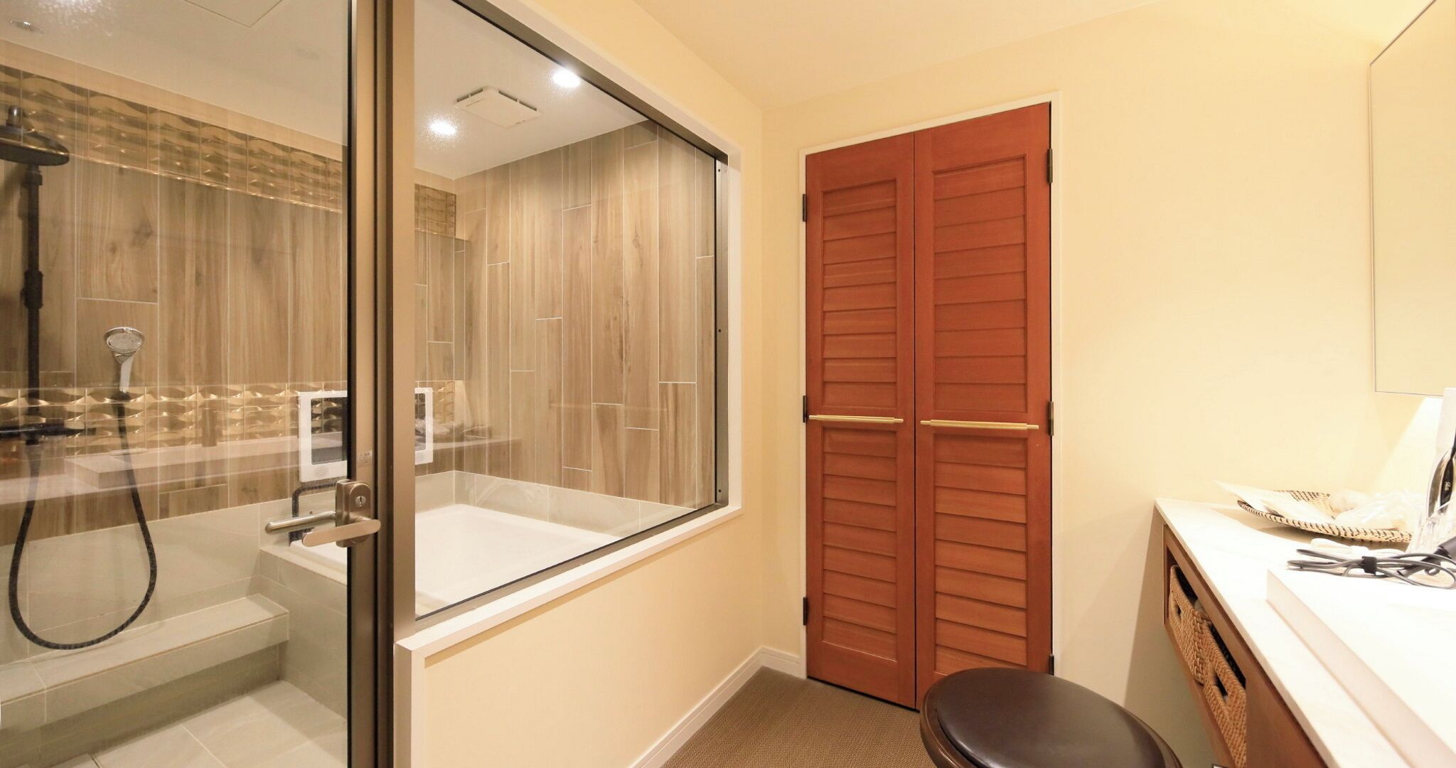 A bathroom with a glass shower enclosure, a wooden door, and a white sink.