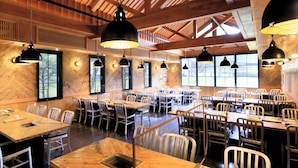 A spacious dining area with multiple tables and chairs, large windows, and hanging pendant lights. - Villa The Club KARUIZAWA (Naganohara)
