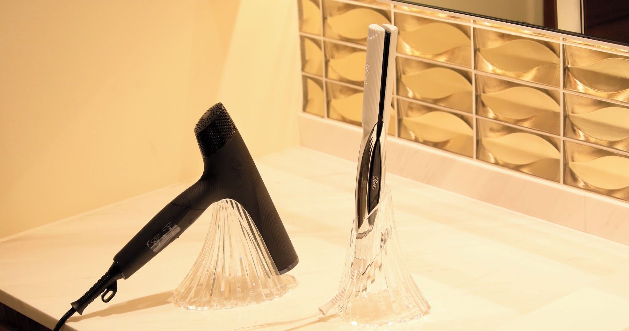Un secador de pelo y un rizador sobre una encimera de baño.