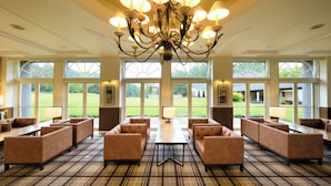 A spacious lobby with a large chandelier, multiple seating areas, and large windows offering a view of the outdoors. - Villa The Club KARUIZAWA (Naganohara)