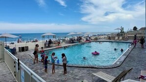 A swimming pool area with a view of the beach, lounge chairs, and umbrellas. - Breathtaking DIRECT Ocean Front (Daytona Beach)