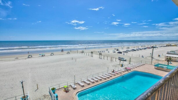A beach view with a swimming pool, lounge chairs, and umbrellas. - Breathtaking DIRECT Ocean Front (Daytona Beach)