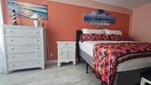 A bedroom with a bed, dresser, nightstand, and artwork on the wall. - Breathtaking DIRECT Ocean Front (Daytona Beach)