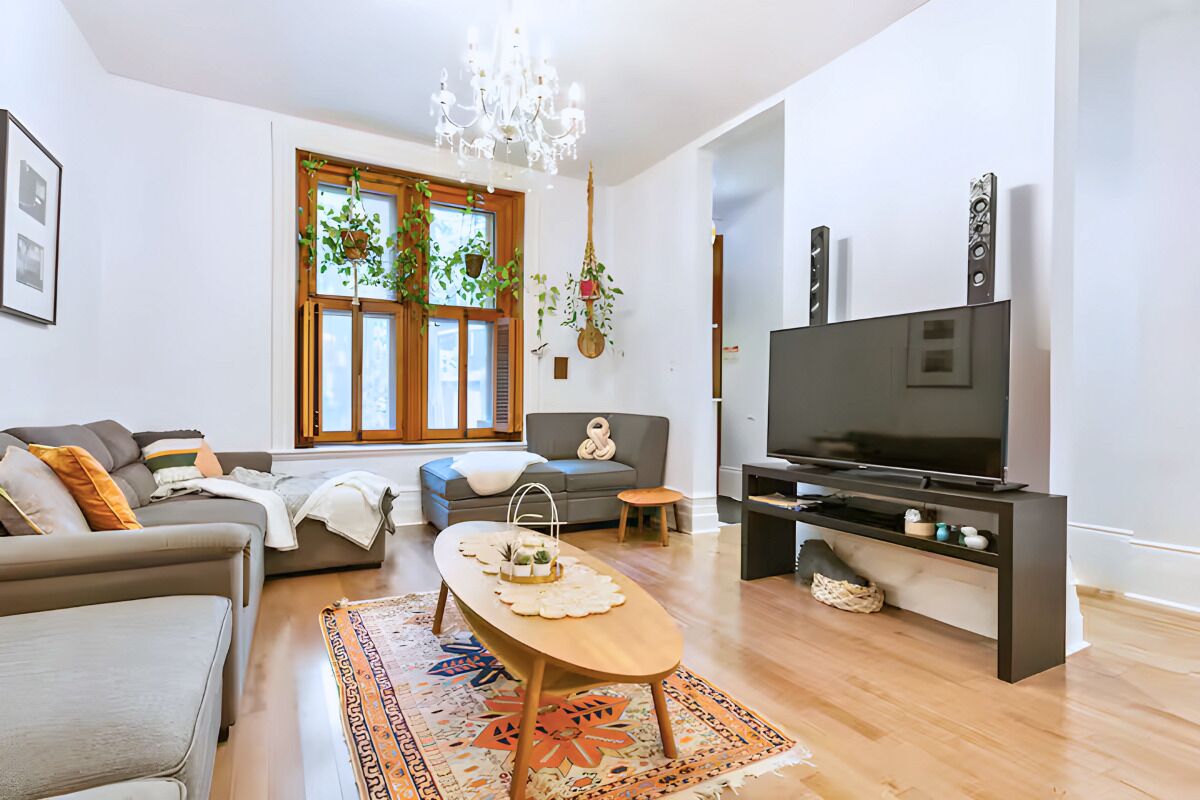 Una sala de estar moderna con sofá, mesa de centro, televisor y candelabro.
