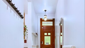 A hallway with a wooden door, a radiator, and a glass shelf unit.