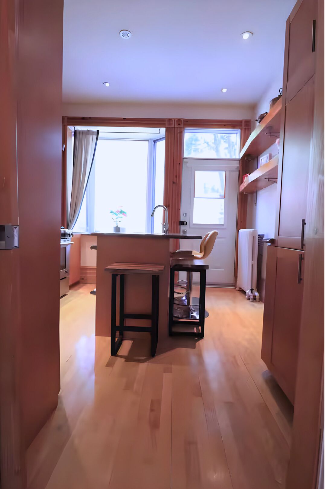 A compact kitchen with wooden cabinets, a small island, and a window providing natural light.