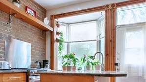 A modern kitchen with a central island, wooden cabinetry, and a large window providing natural light.