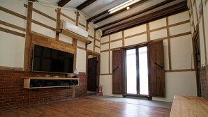 Une pièce spacieuse dotée d’un plancher en bois, d’un meuble de rangement intégré pour les appareils multimédias et d’une grande porte coulissante.