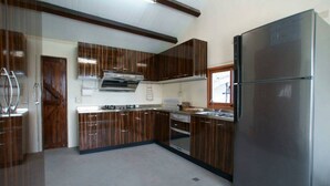 Une cuisine moderne avec des meubles en bois foncé, des appareils électroménagers en acier inoxydable et un grand réfrigérateur.