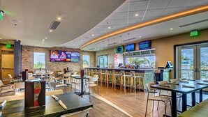 A modern restaurant with a bar area, multiple seating options, and a television screen displaying news. - Free Shuttle,Official Encore Water Park,XBOX,Movie,Games,Cage,Pool/Spa,Star Wars (Kissimmee)
