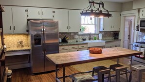 A kitchen with white cabinets, stainless steel appliances, a wooden island, and a window providing natural light.