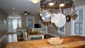 A kitchen with a wooden table, hanging pots, and a wicker basket.