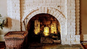 A white brick fireplace with a decorative mantel, a woven basket, and a painting above it.