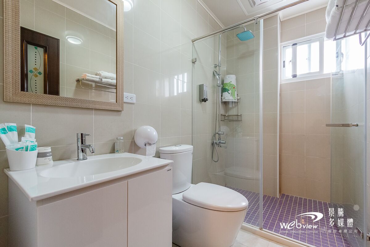 A modern bathroom with a glass-enclosed shower, a white sink, and a toilet.