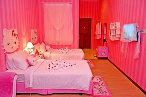 Una habitación con temática rosa, con dos camas, un tocador con espejo y decoración inspirada en Hello Kitty.