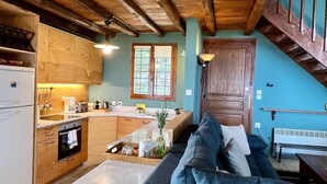 A compact kitchen with wooden cabinets, a built-in oven, and a dining area with a sofa and table. - PELION HOMES | Villa SELINI large traditional villa w/ pool & breathtaking view (Agios Georgios Nilias)