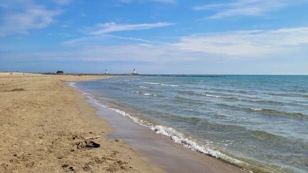 A sandy beach with gentle waves, a lighthouse in the distance, and a clear sky. - Villa-type ground floor apartment with spacious private terrace - sleeps 4 (Agde)