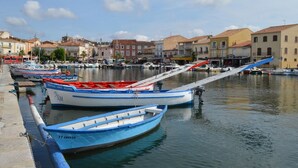 A marina with several small boats docked, a clear sky, and buildings in the background. - Villa-type ground floor apartment with spacious private terrace - sleeps 4 (Agde)