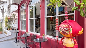 A red building with large windows, outdoor seating, and decorative lanterns. - Talakkia Boutique Hotel (Bangkok)