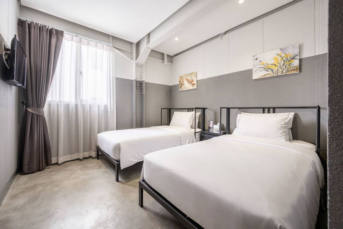 Habitación de hotel con dos camas, televisión y obras de arte en las paredes.