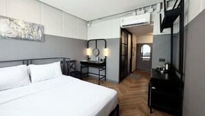 Een hotelkamer met een bed, bureau, stoel en een spiegel.