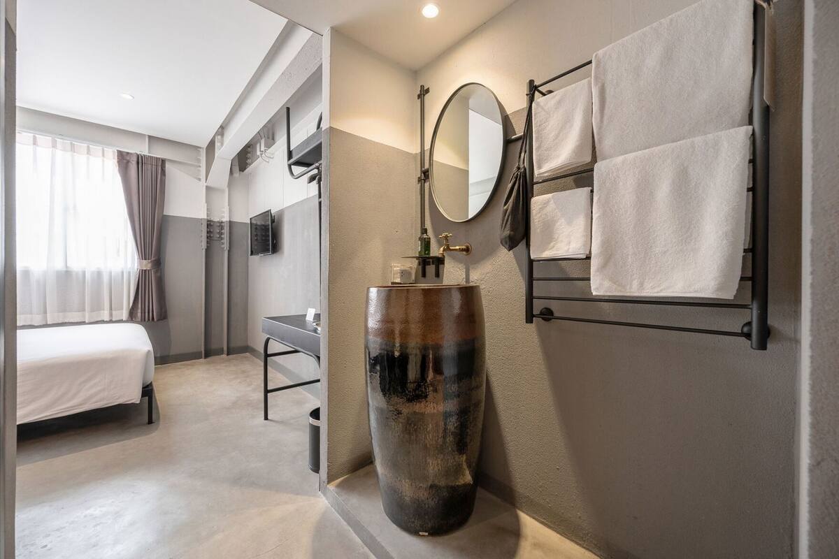 Un baño moderno con un lavabo de cerámica grande, un espejo y un perchero para toallas.