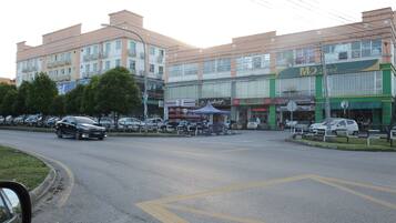 A multi-story building with various shops on the ground floor, including a car accessories store and a restaurant.