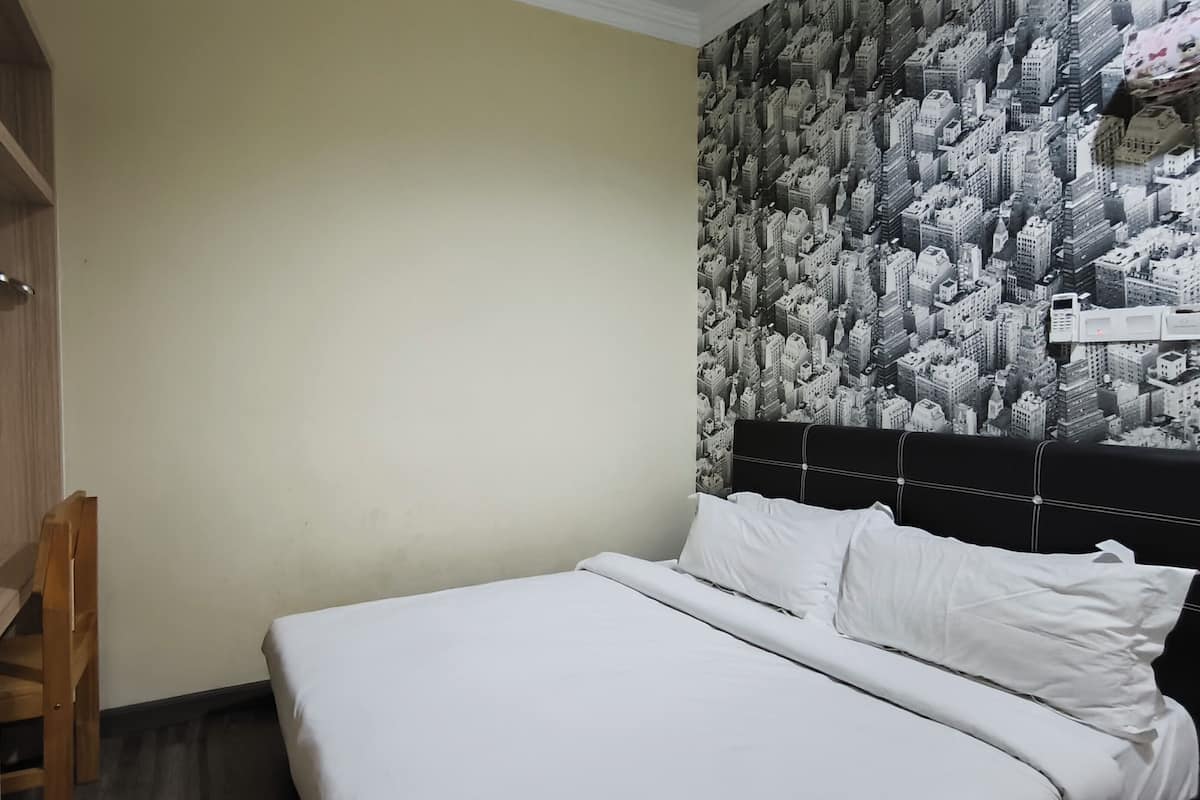 A hotel room with a bed, a wardrobe, and a wall with a cityscape wallpaper.