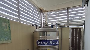 Une pièce équipée d’un grand distributeur d’eau en acier inoxydable sur le thème de King Kong, d’une étagère en métal et d’une porte avec un tuyau.
