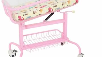 Een roze babybedje op wielen met een transparante plateau.