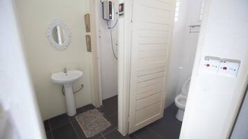 A bathroom with a white sink, a toilet, and a shower area.