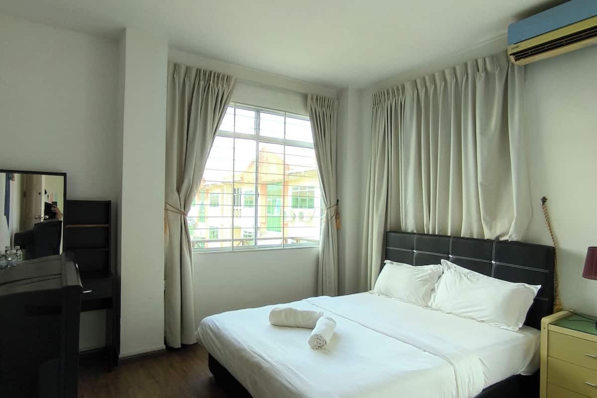 A hotel room with a bed, a desk, and a window with curtains.