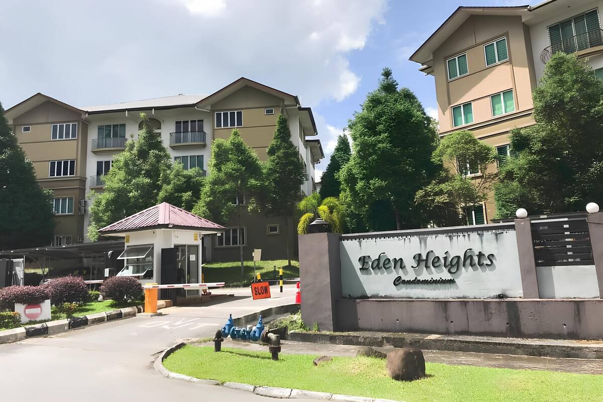 A multi-story residential building with a gated entrance, a sign reading "Eden Heights Condominium," and a clear sky.