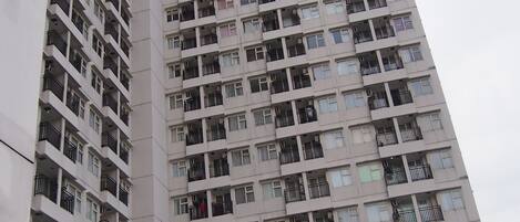 A high-rise residential building with multiple balconies, air conditioning units, and a uniform architectural style.