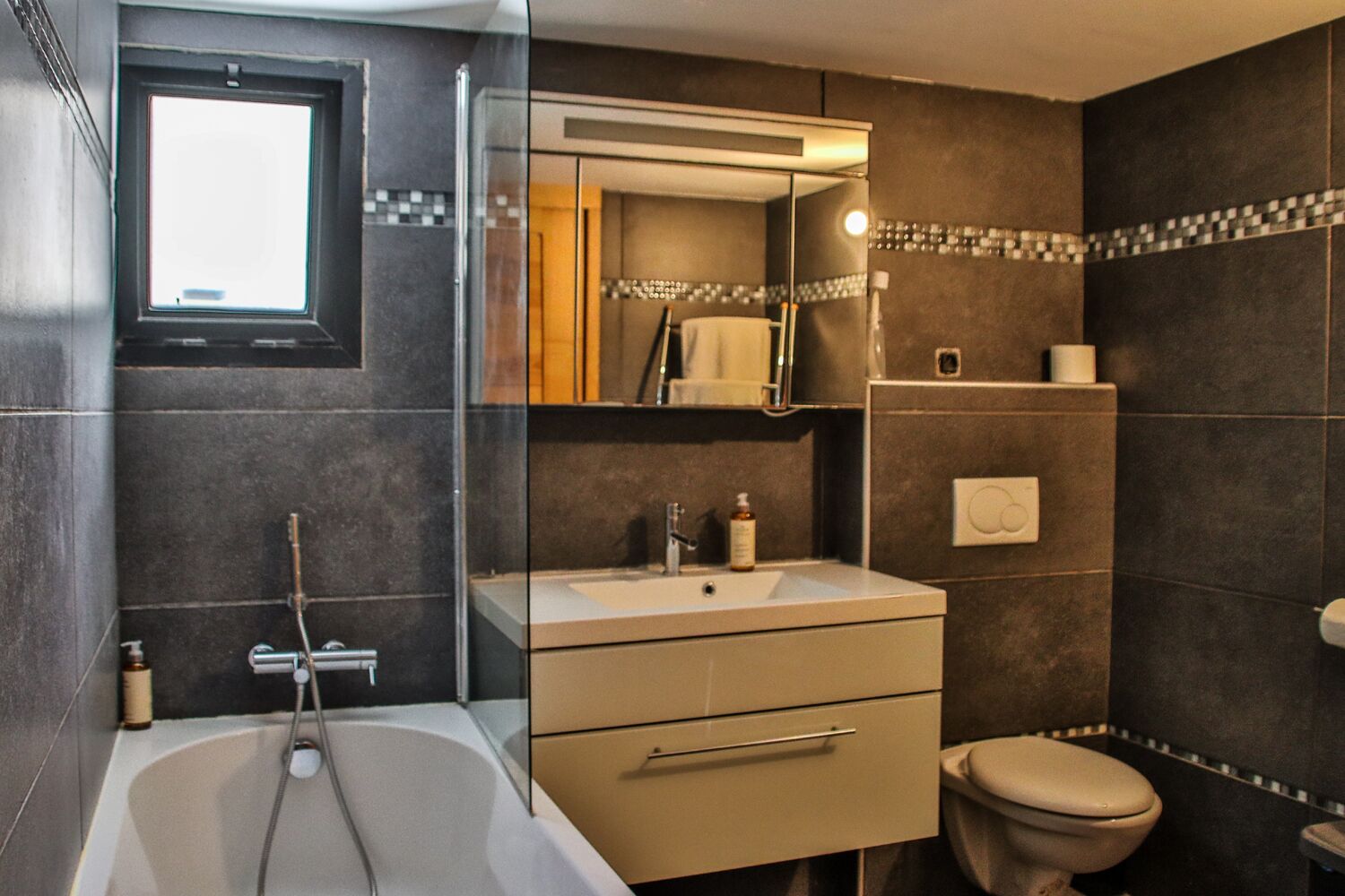 Un baño moderno con bañera, lavabo, inodoro y un espejo grande.