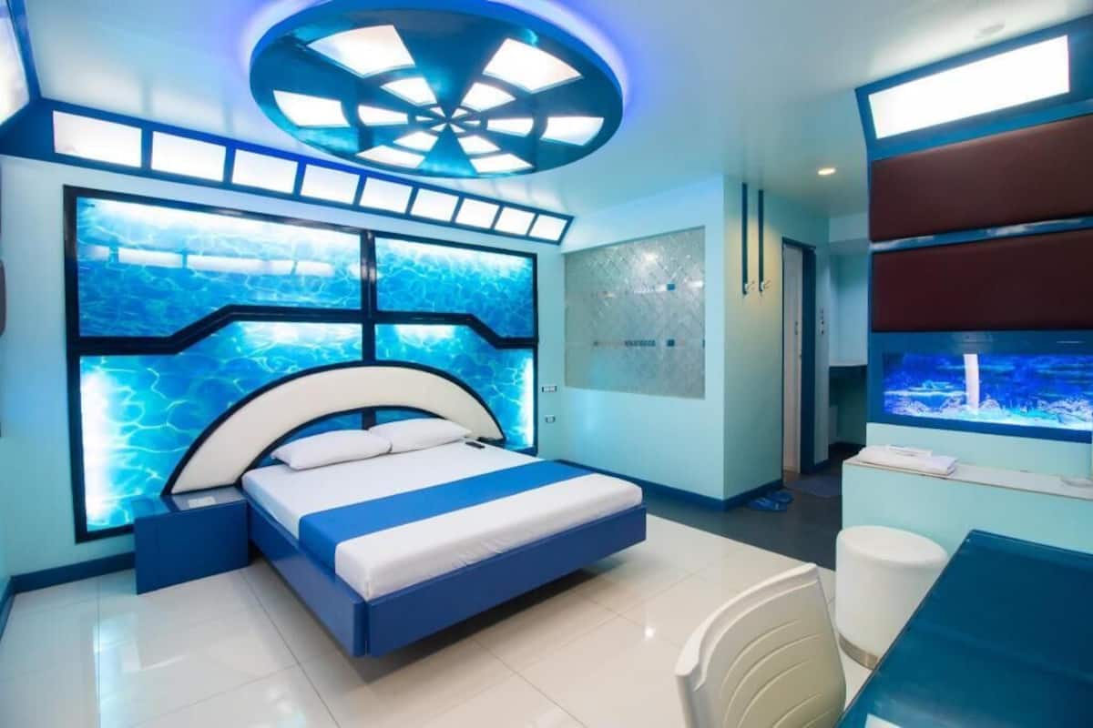A modern bedroom with a bed, a large window, and a circular ceiling light fixture.