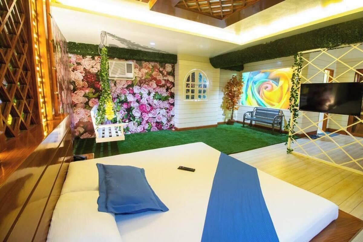 A room with a bed, a TV, a wall with floral wallpaper, and a small garden area.