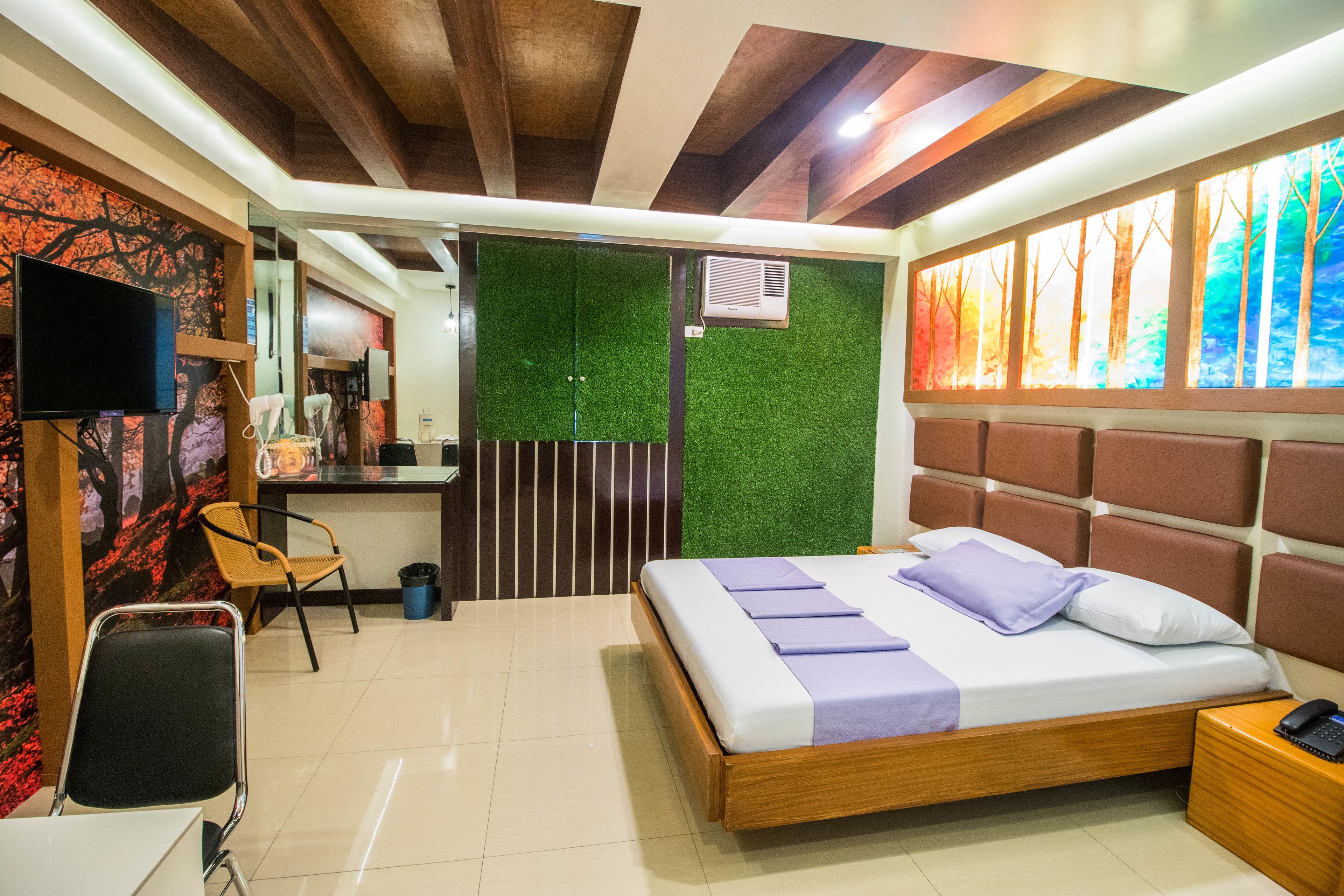 A hotel room with a bed, a desk, a chair, and a TV.