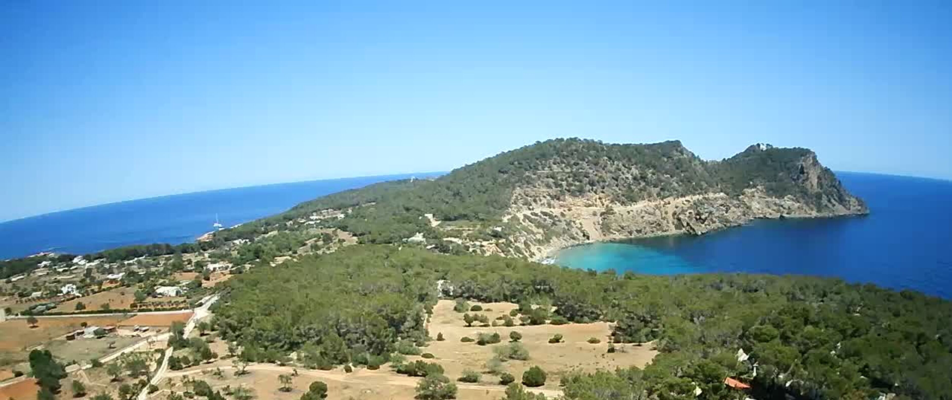 A coastal landscape with a prominent hill and a small settlement.