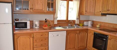 A kitchen with wooden cabinets, a microwave, a dishwasher, a sink, and a stove.